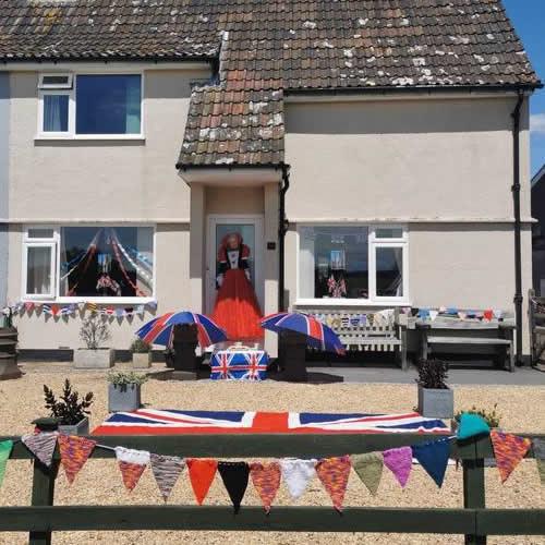 Photo Gallery Image - 'The Queen' in crimson dress with Union Jack umbrellas