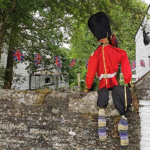 Photo Gallery Image - A Queen's Guard in red tunic and bearskin hat and stripy socks