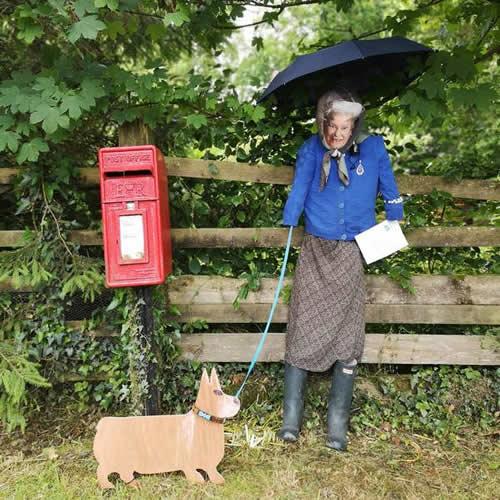 Photo Gallery Image - 'The Queen' with a corgi posting a letter at the post box 